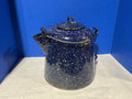 Blue speckled enamel teapot on a white surface with a blue background