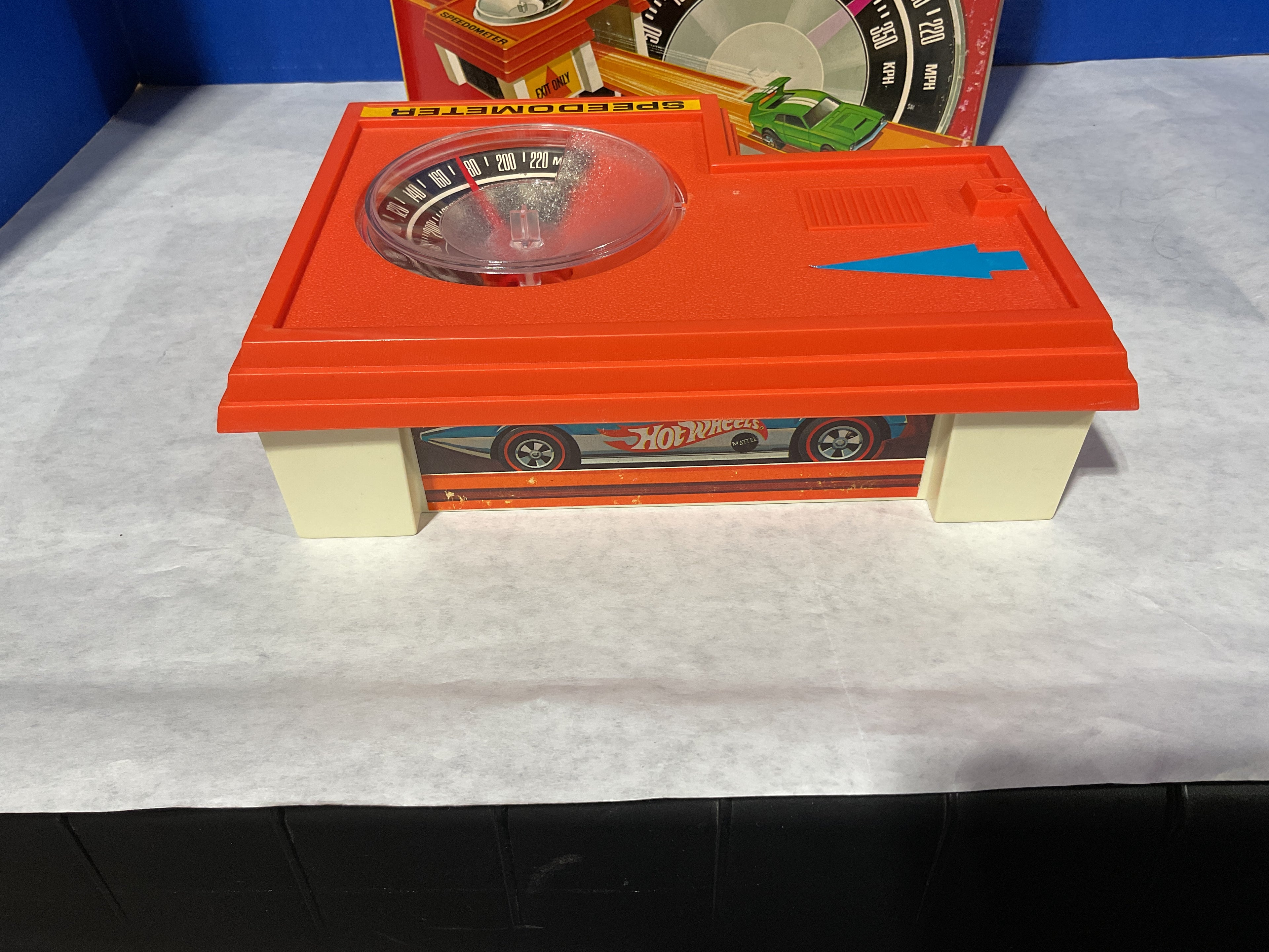Toy speedometer with a Hot Wheels car on a white surface